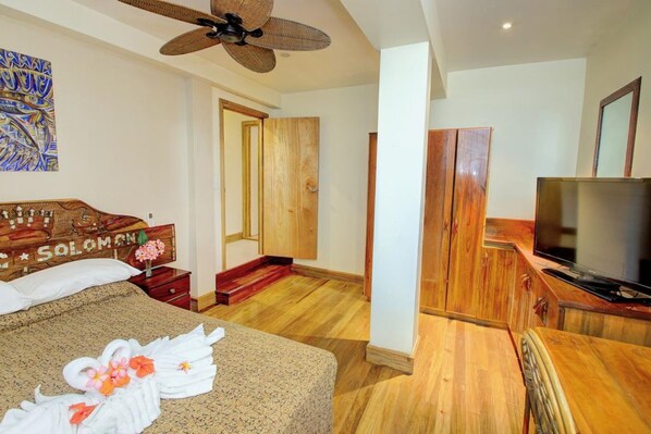 A hotel room with a bed, a television, wooden furniture, and a ceiling fan. - King Solomon Hotel (Honiara)