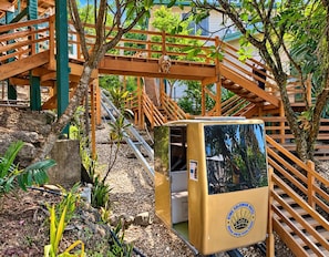 A wooden staircase with a small yellow kiosk labeled 'King Solomon Hotel' in a garden setting. - King Solomon Hotel (Honiara)