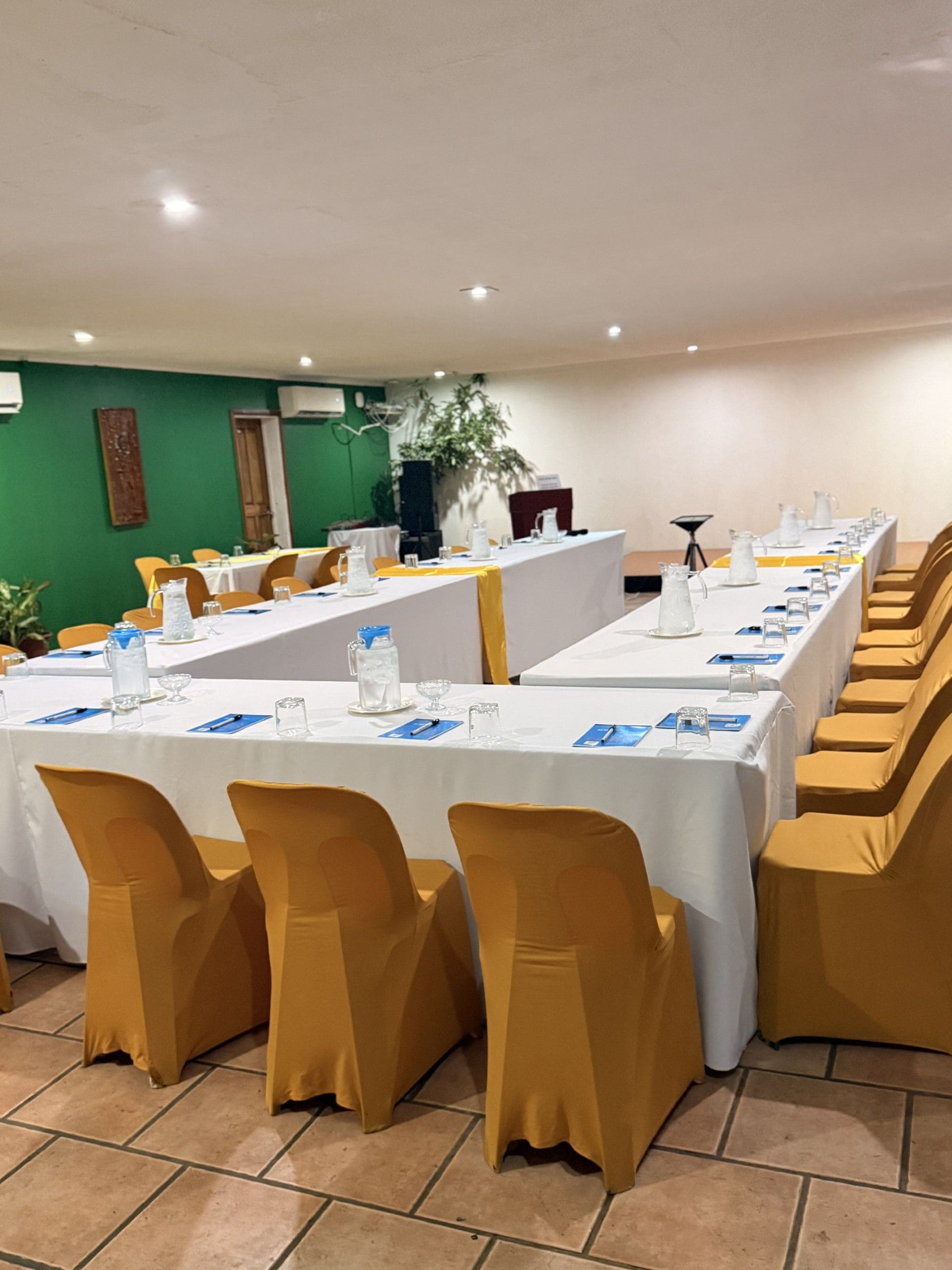 A conference room with long tables, chairs, and a green wall.