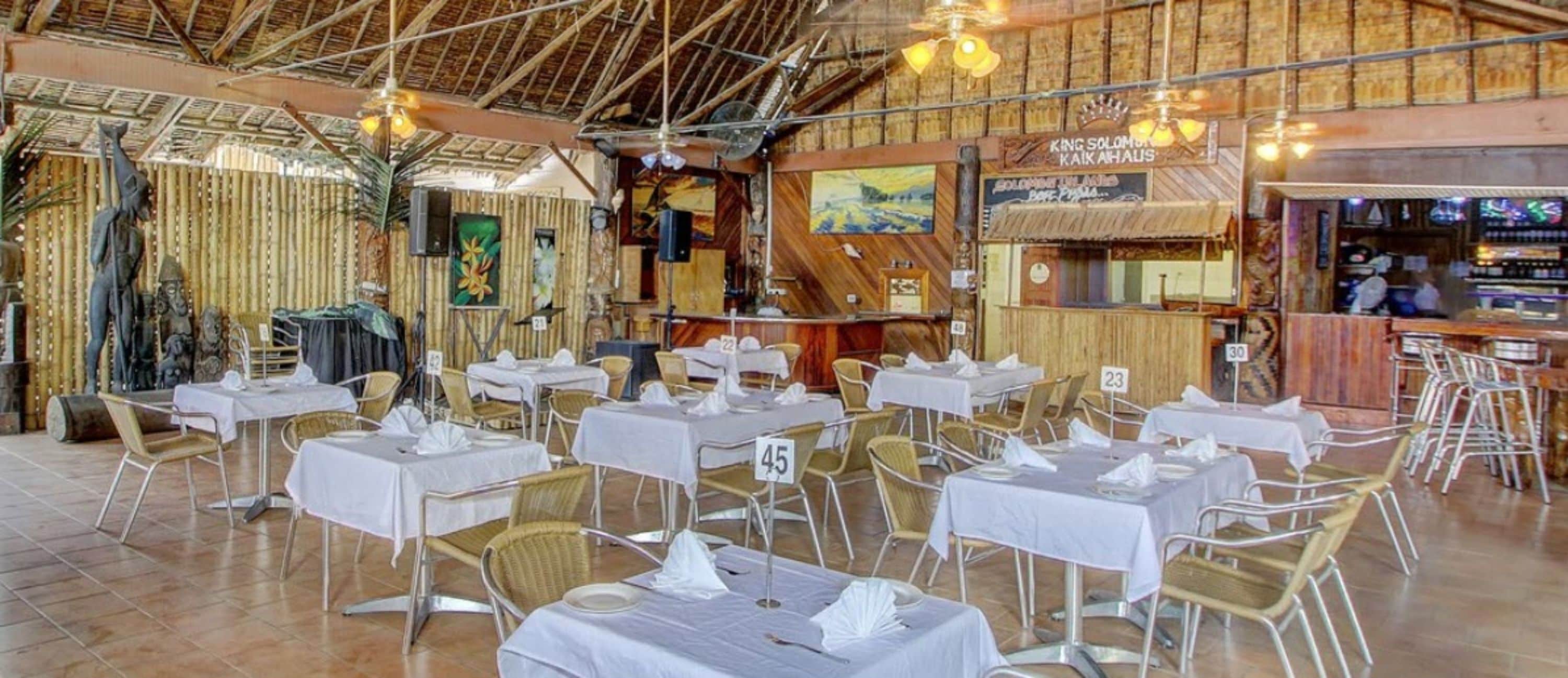 Un restaurant doté de nombreuses tables et chaises, d’un bar et d’une fresque murale.