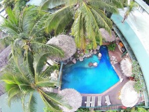 A pool surrounded by palm trees and thatched umbrellas, with a clear blue water feature. - King Solomon Hotel (Honiara)