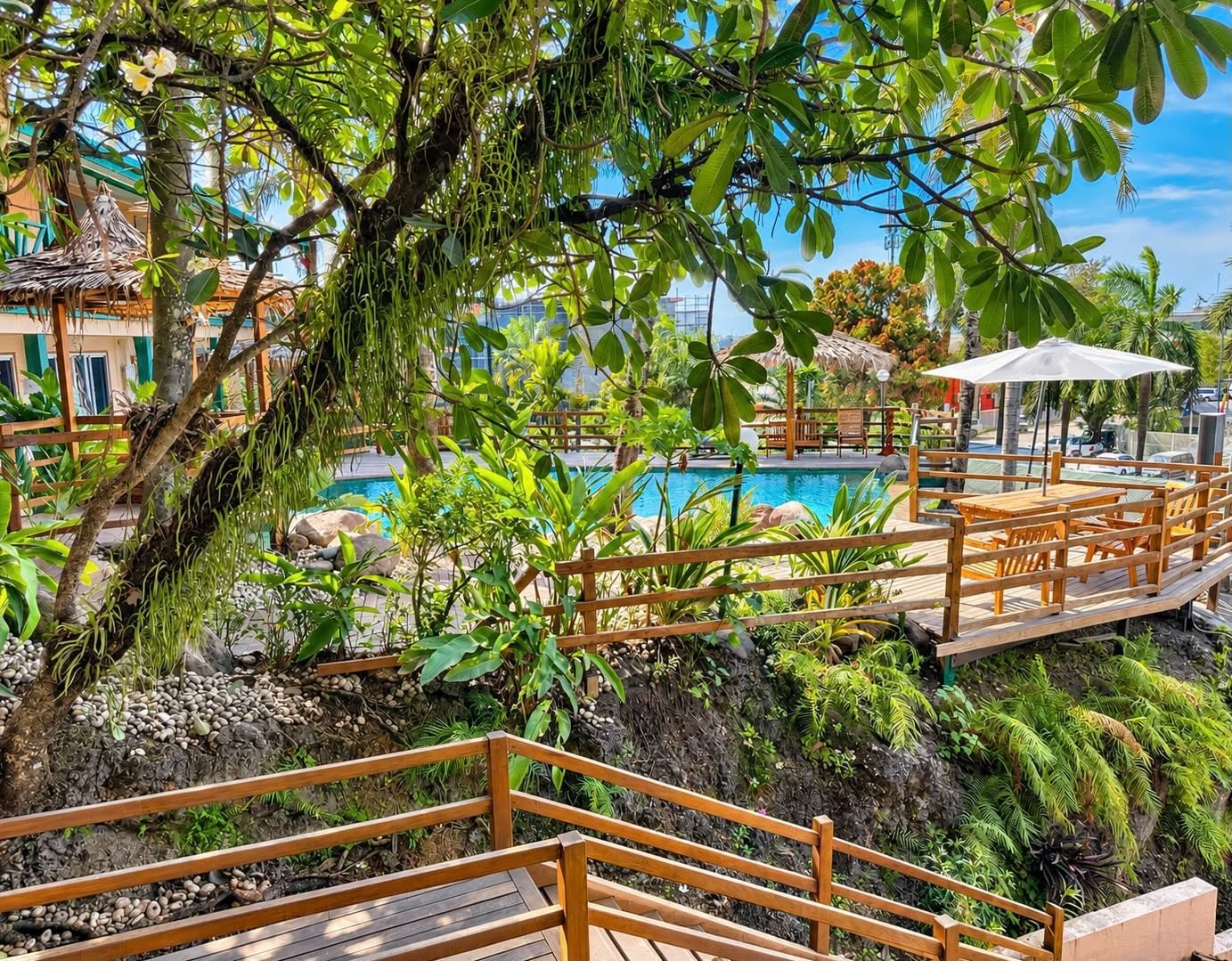A wooden deck with a pool and tropical plants.