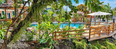 A wooden deck with a pool and tropical plants.