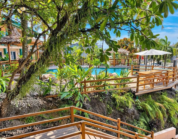 A wooden deck with a pool and tropical plants. - King Solomon Hotel (Honiara)