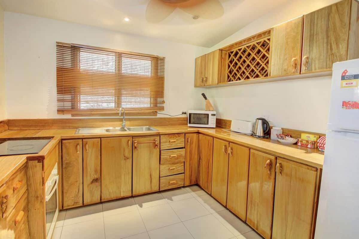 A kitchen with wooden cabinets, a microwave, a sink, and a refrigerator.