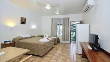 A hotel room with two beds, a desk, a TV, and a ceiling fan.