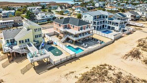 Et kystnært boligområde med huse, en swimmingpool og en strand.