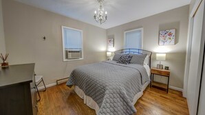 Een slaapkamer met een bed, nachtkastjes, een kroonluchter en kunstwerken aan de muren.