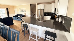 Une cuisine moderne avec des meubles blancs, un plan de travail noir et un îlot central doté de tabourets de bar.
