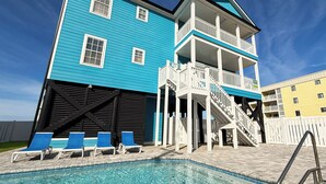 Un immeuble à plusieurs étages doté d’un espace piscine, comprenant des chaises longues et un escalier menant à un balcon.
