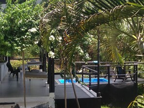 A pool area with a wooden deck, lounge chairs, and a small waterfall feature. - Casa Massalli (San Andrés)