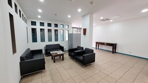 Ein Wartebereich mit schwarzen Sofas, einem Holztisch und einer blau gerahmten Bank.