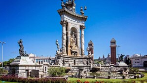 Un monument historique à l’architecture classique, orné de colonnes et de statues, entouré d’un jardin bien entretenu où fleurissent de magnifiques plantes.