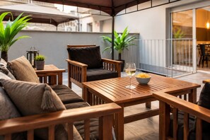 Un espace extérieur aménagé en bois, avec une table, des chaises et un saladier rempli de collations.