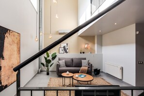 Een moderne woonruimte met een trap, een bank, twee bijzettafeltjes en een radiator.