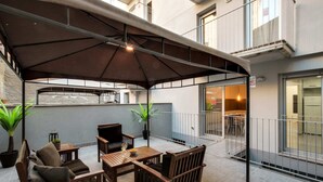 Un patio couvert aménagé avec du mobilier en bois, comprenant une table et des chaises, ainsi que des plantes en pot.