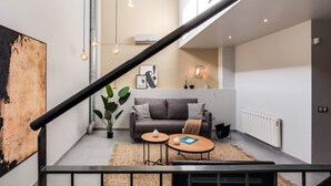 Un salon moderne avec un canapé, deux petites tables et un escalier.