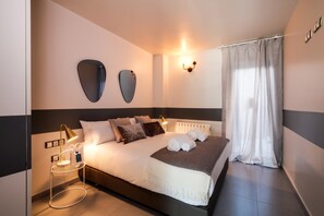 Een hotelkamer met een bed, bedlampen, een wandlamp en een raam met gordijnen.