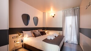 Une chambre d’hôtel moderne, dotée d’un grand lit, de lampes de chevet, d’un miroir fixé au mur et d’une fenêtre avec des rideaux légers.