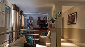 A modern lobby with a reception desk, seating area, and a staircase. - Hotel Brickell (Lima)