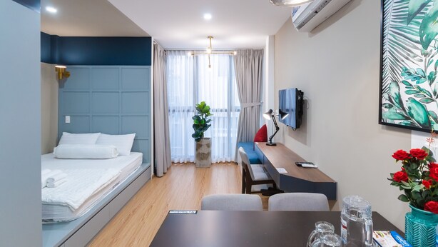 Ein modernes Hotelzimmer mit Bett, Schreibtisch, Stuhl und einem großen Fenster mit Vorhängen.