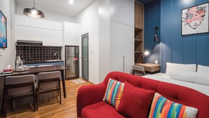 Ein kleines Hotelzimmer mit Küchenzeile, einer Essecke, einem roten Sofa und einem Bett.