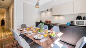 A modern kitchen with a dining table set for breakfast, including plates, glasses, and a fruit bowl. - Sweett | Rocafort 103 (Barcelona)