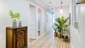 A hallway with patterned floor tiles, a wooden cabinet with vases, and potted plants. - Sweett | Rocafort 103 (Barcelona)