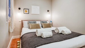 A hotel room with a bed, pillows, a blanket, and two wall-mounted lights. - Sweett | Rocafort 103 (Barcelona)