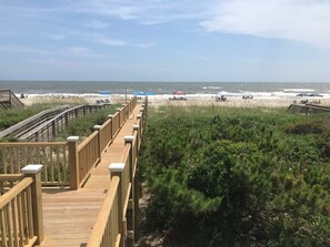Un paseo marítimo de madera que conduce a una playa, con vista clara al océano y la orilla arenosa.