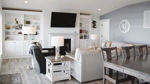 Un salon avec une cheminée, un téléviseur, une table à manger et un canapé.