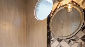 A modern bathroom with a round mirror, a vessel sink, and a toilet.