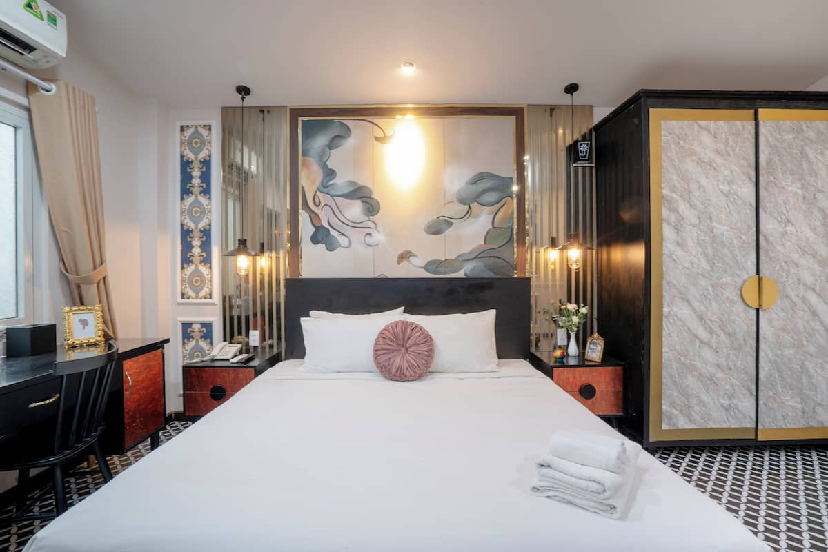 A hotel room with a large bed, a desk, a wardrobe, and a decorative wall.