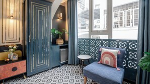 A room with a patterned floor, a blue sofa with a decorative pillow, a small round table, and a cabinet with a geometric design.