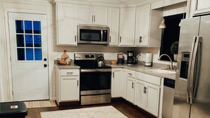 A kitchen with white cabinets, stainless steel appliances, a microwave, oven, coffee maker, and a refrigerator. - CritzerShop - route 151- walk to the Brewey! (Afton)