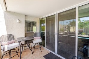 Un patio couvert avec une table et des chaises, une porte-fenêtre coulissante et une vue sur l’extérieur.