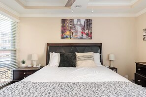 A hotel room with a large bed, a painting of a cityscape, a nightstand, a lamp, and a window with blinds. - Balcony-Pool View*Resort Feel*Walk Everywhere (Scottsdale)