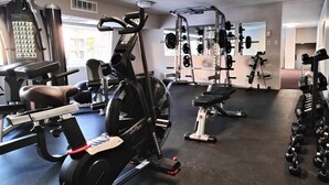 Ett gym med konditionsmaskiner, styrketräningsstationer och hantlar.