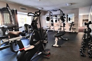 A gym with cardio equipment, weightlifting stations, and dumbbells.