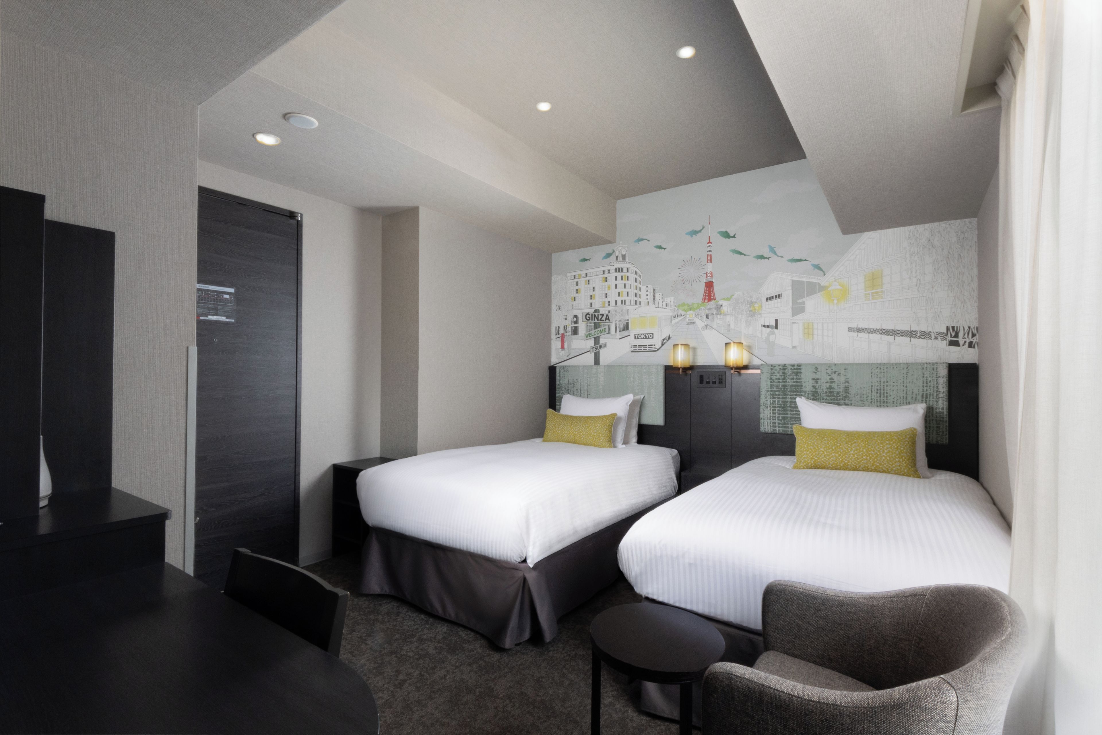 A hotel room with two beds, a desk, and a chair.
