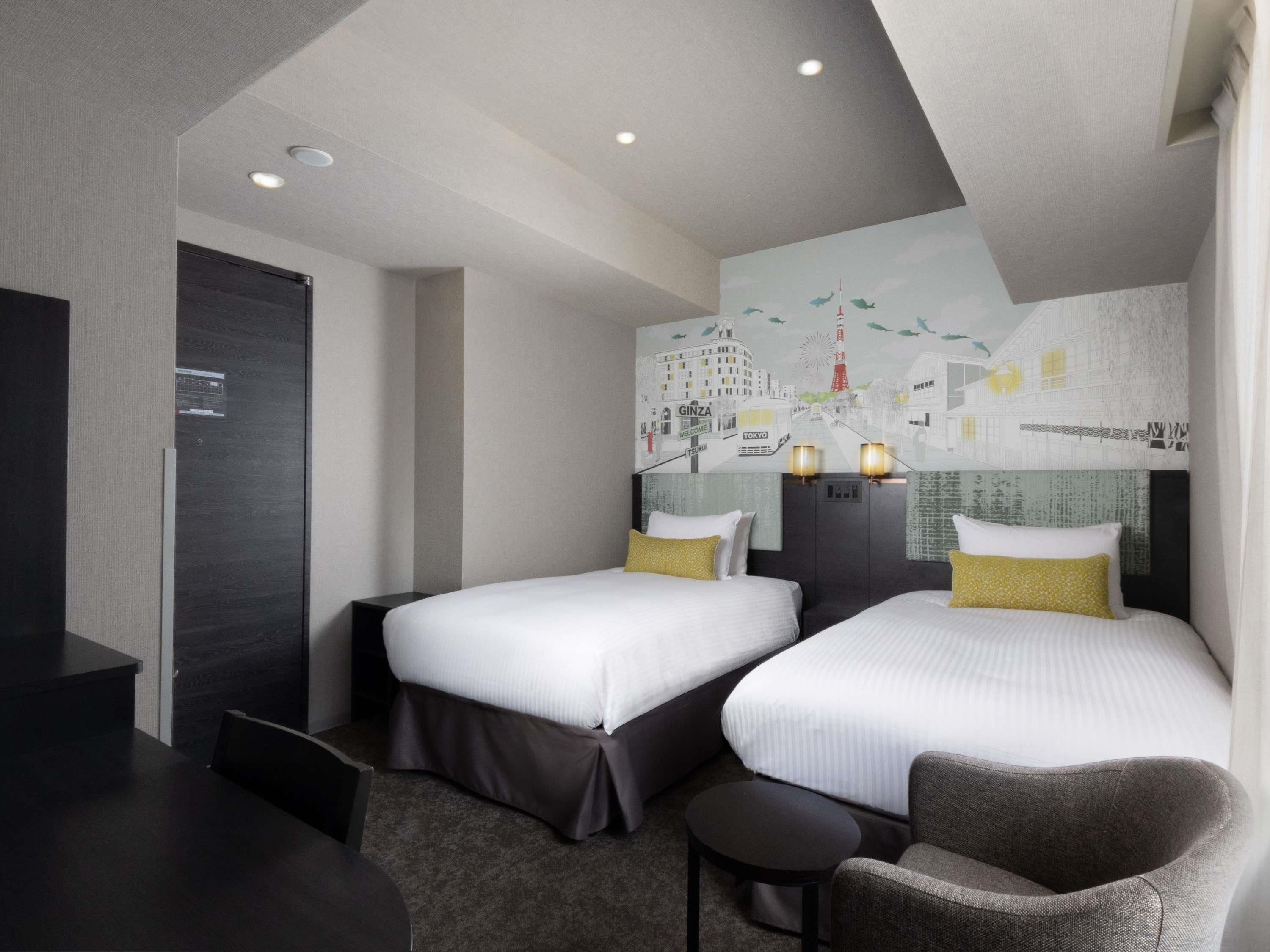 A hotel room with two beds, a desk, and a chair.