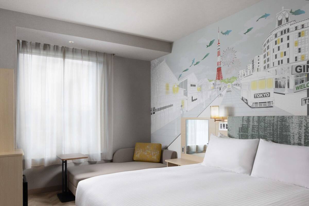 Une chambre d’hôtel avec un grand lit, un bureau, une chaise et une fresque murale.