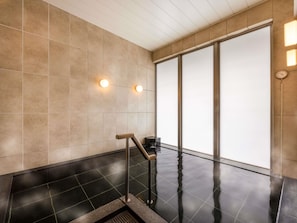 Een moderne badkamer met een zwart betegelde vloer, beige wanden en een groot raam met gebroken glas.