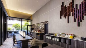 Una cocina moderna con una encimera larga, un comedor con baldosas hexagonales y un amplio ventanal con vistas a zonas verdes.