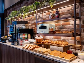 A breakfast buffet with pastries, bread, and beverages.