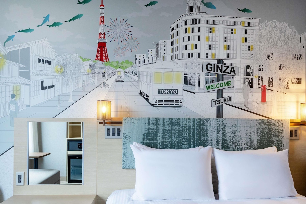 Een hotelkamer met een bed, nachtkastje, lamp en een muurschildering met bezienswaardigheden van Tokio.