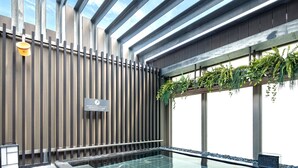 Un área de piscina interior moderna con piso de vidrio, jardín vertical y un cartel en la pared.