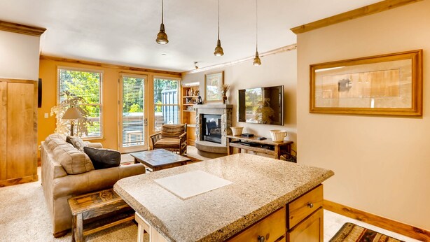 A cozy living room with a fireplace, a dining area, and a kitchen with granite countertops. - Spacious 1br -river Run Village-hot Tub & Kids Ski Free 1 Bedroom Condo by RedAwning (Keystone)
