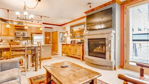 A spacious living room with a fireplace, wooden furniture, and a large TV mounted above the fireplace. - Updated 1br Premier  At Black Bear Lodge- Kids Ski Free 1 Bedroom Condo by RedAwning (Keystone)