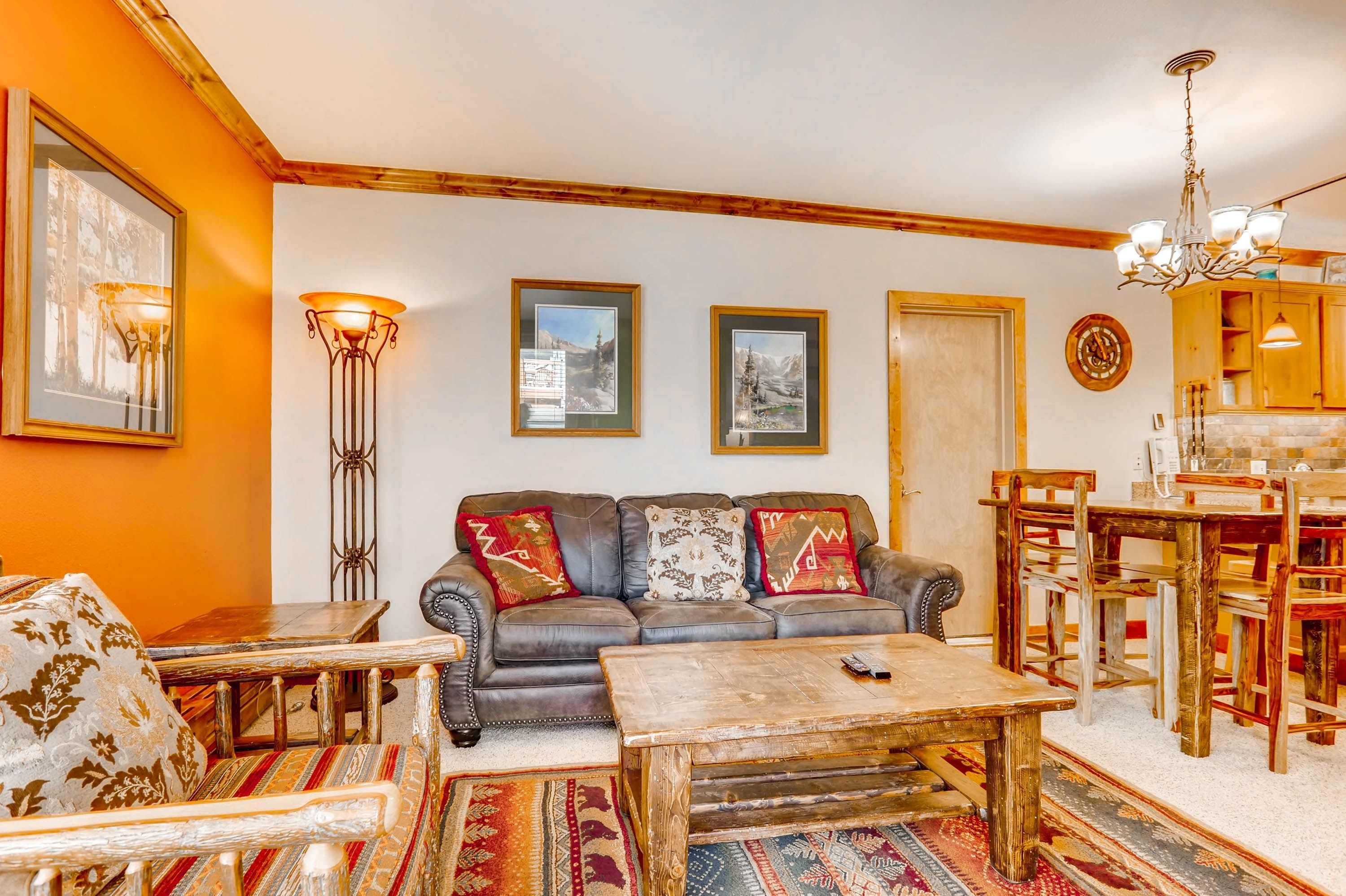 A cozy living room with a sofa, coffee table, and a dining area with wooden chairs and a table.